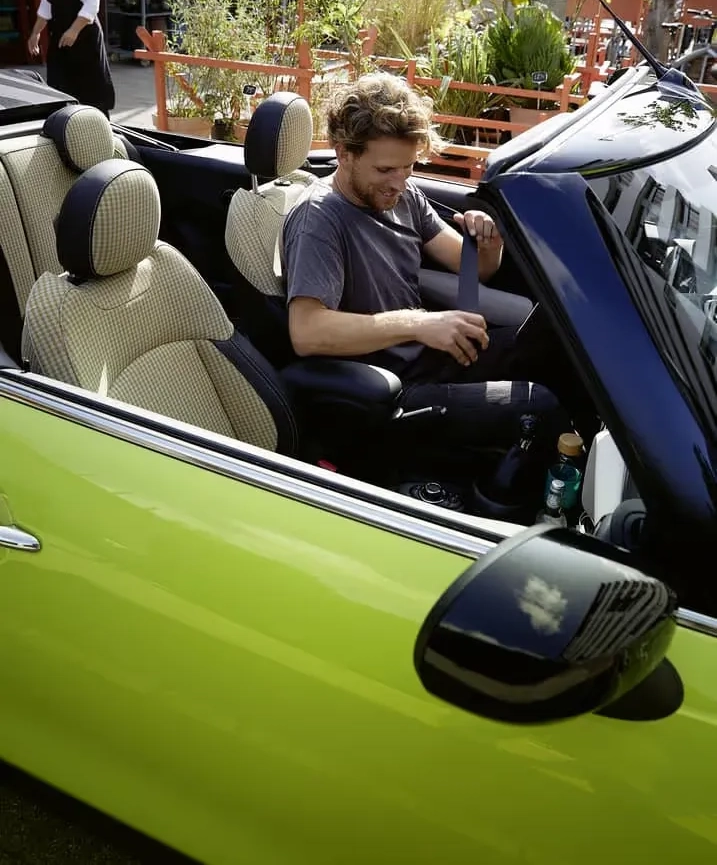 Young man sitting in a bright green MINI